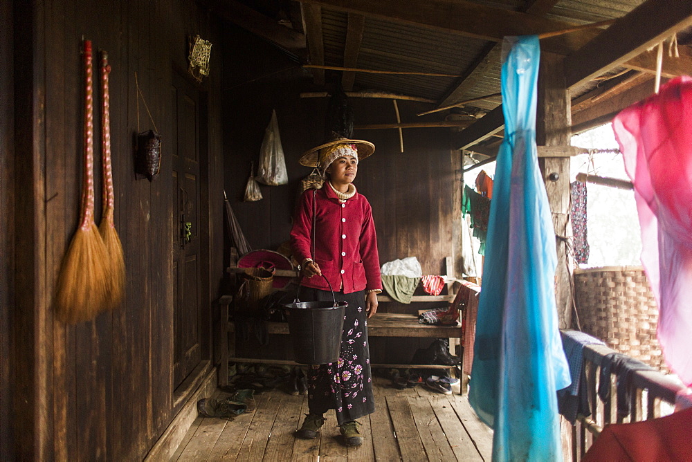 Portrait of young woman standing on porch with bucket in hand, Myanmar, Shan, Myanmar