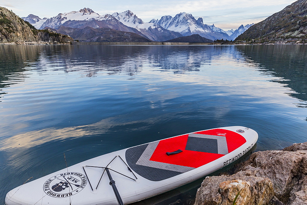 Paddle board near rocky shore on lake in front of mountains, Emosson Dam, Wallis, Switzerland