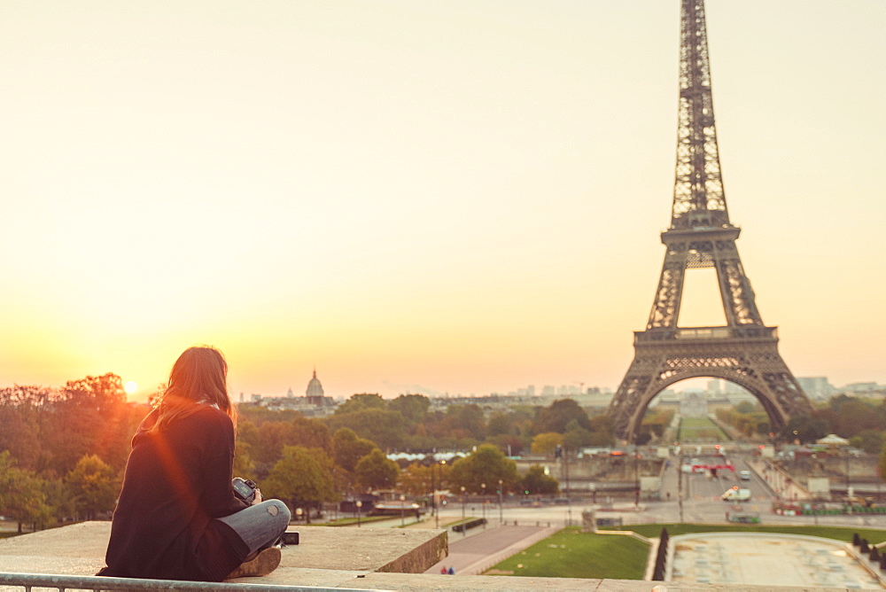 Young lady sitting and looking at Eiffel Tower at sunset, Paris, Ile-de-France, France