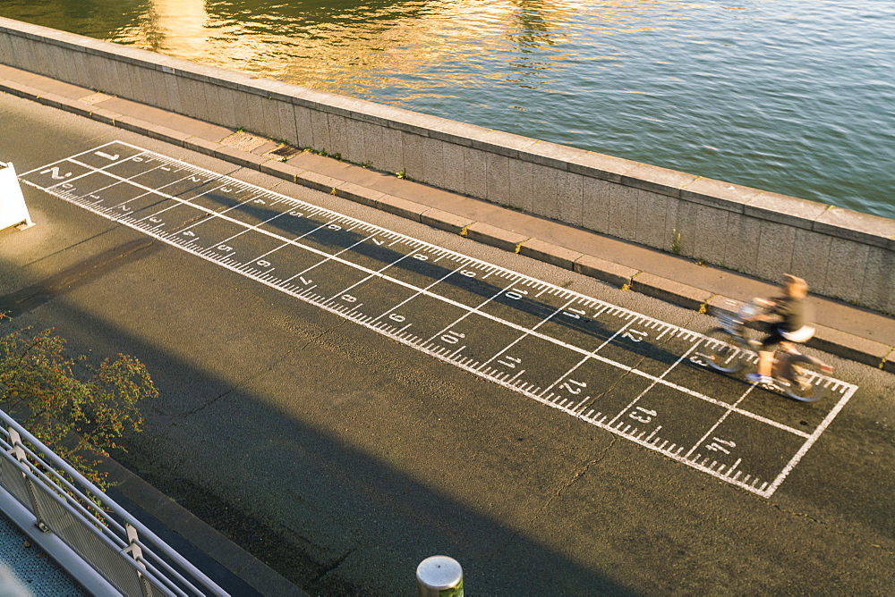 High angle view of biker on banks of Seine River early morning in Paris, Ile-de-France, France