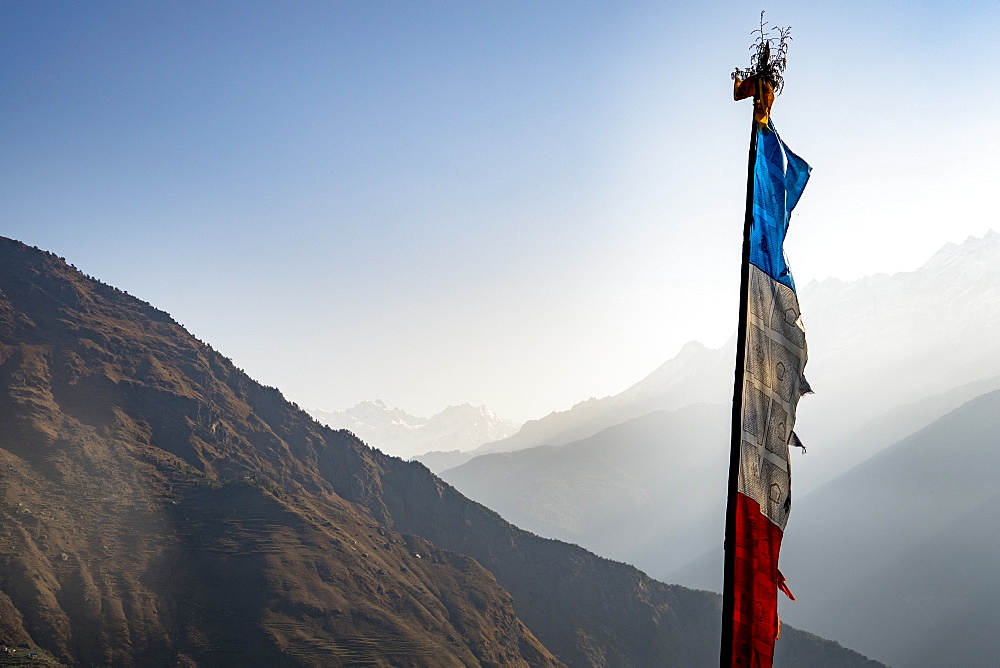 Prayer flag against sky and foggy mountain valley, Goljung, Rasuwa, Nepal