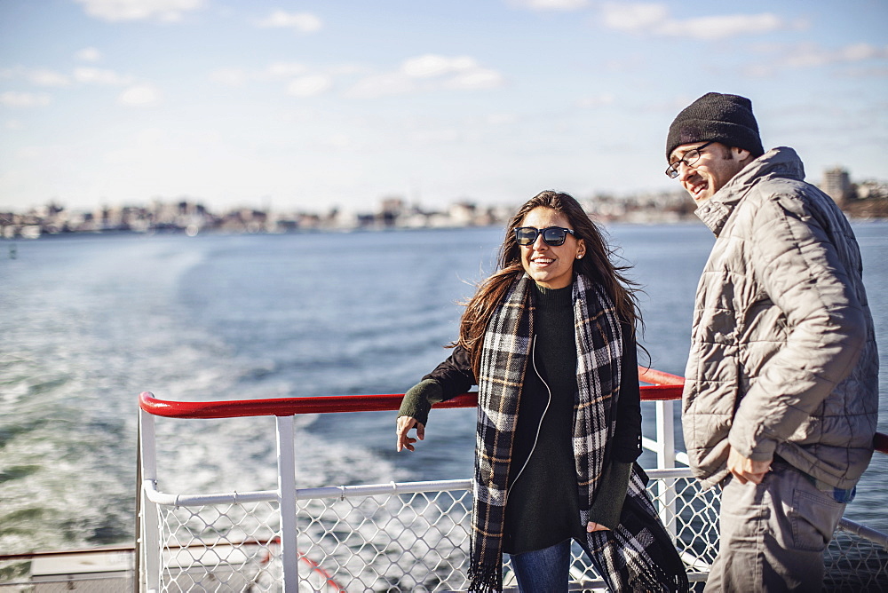 Two friends leaning on railing while riding ferry to Peaks Island, Portland, Maine, USA