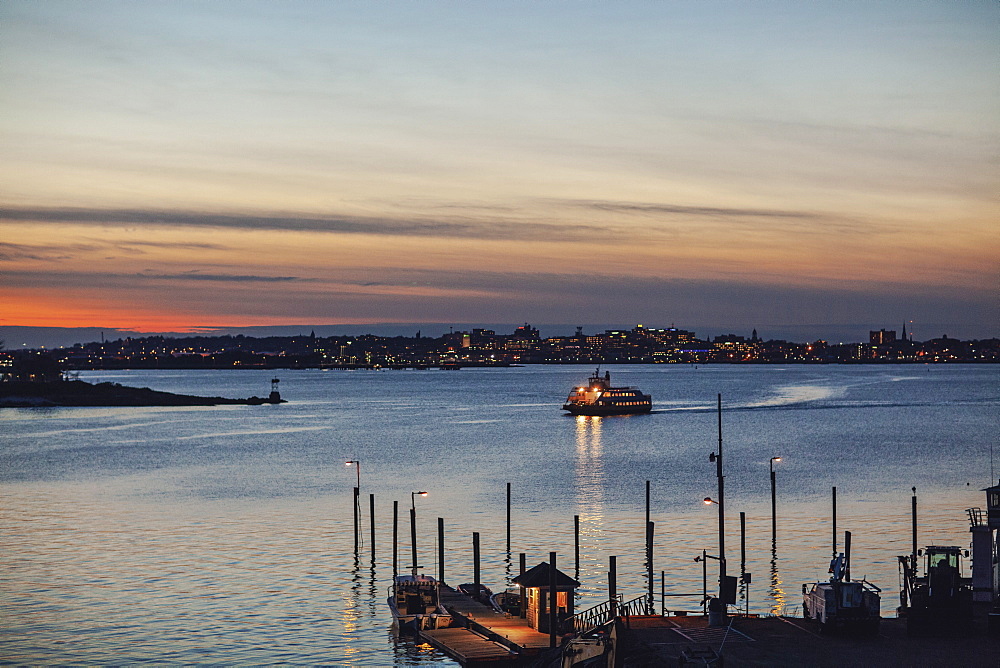 Silhouette of ferry arriving at harbor of Peaks Island at dusk, Portland, Maine, USA