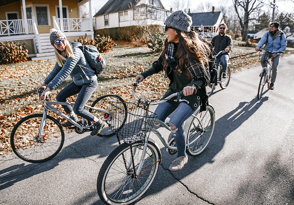 Group of friends biking through sunny village in autumn, Portland, Maine, USA