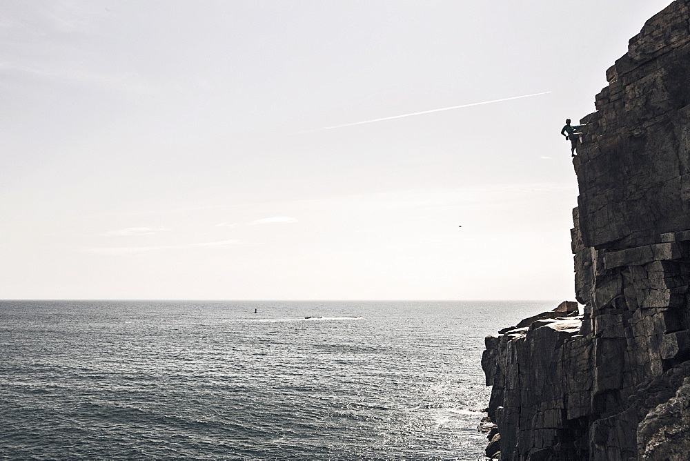 Man climbing on Otter Cliffs overlooking sea, Acadia National Park, Maine, USA