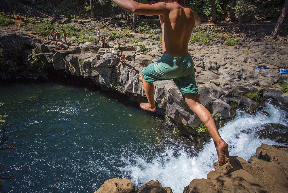 Rear view of single shirtless young man cliff jumping into?McCloud?River, California, USA