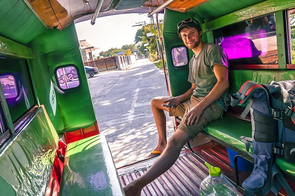 Smiling young man sitting in motor rickshaw and looking at camera, Â ChiangÂ Mai, Thailand