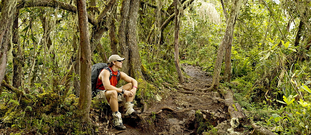 A young man rests after hiking in the jungle 13,000ft. below Mt. Kilimanjaro's summit.