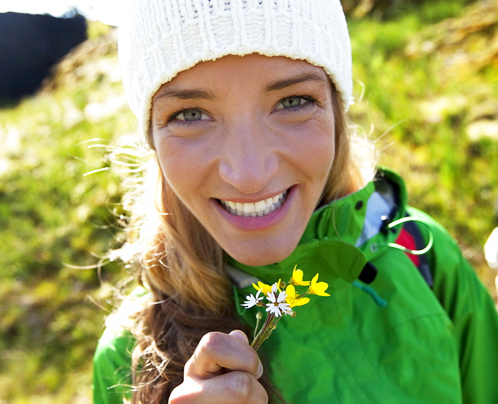 A woman out  smiling with fresh picked flowers.