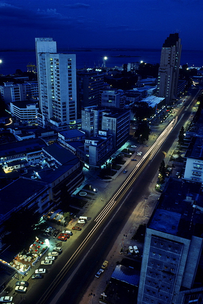 Scene of downtown Kinshasa at dusk showing the main street, the 20th Juin, cutting through the city.