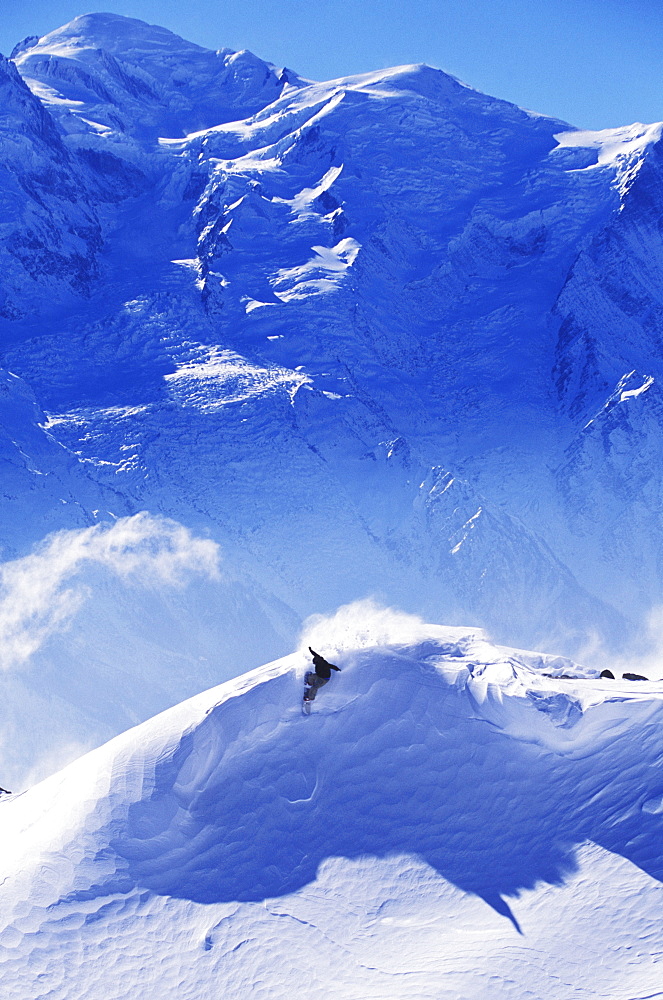 Early one winter morning, a snowboarder makes a turn underneath Mt. Blanc, Europest tallest mountain. Chamonix, France.