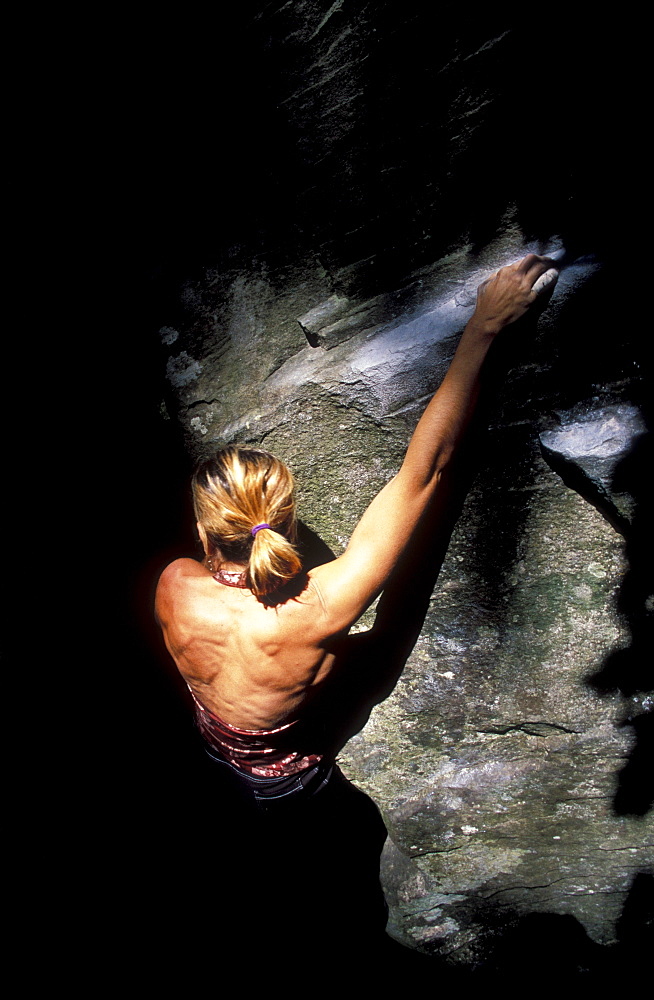 Rock climber Cassandra Riddle climbs out of the shadows while climbing at Carver, Oregon.