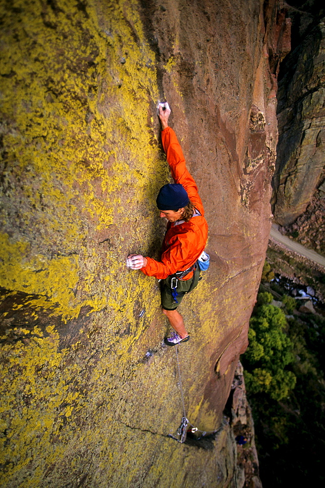 Bruce Miller climbs on the hardest part, or "crux", of a route called "Jules Verne", rated 5.11a, high off the ground on the Redgarden Wall in Eldorado Canyon State Park, CO.  Jules Verne is one of the more famous traditional or "trad" routes in the area, and has long sections between protection. Eldorado Canyon, located on the Front Range south of Boulder, and  its steep, difficult sandstone cliffs attract climbers from around the country and the world, making it one of  the most popular climbing areas in Colorado.