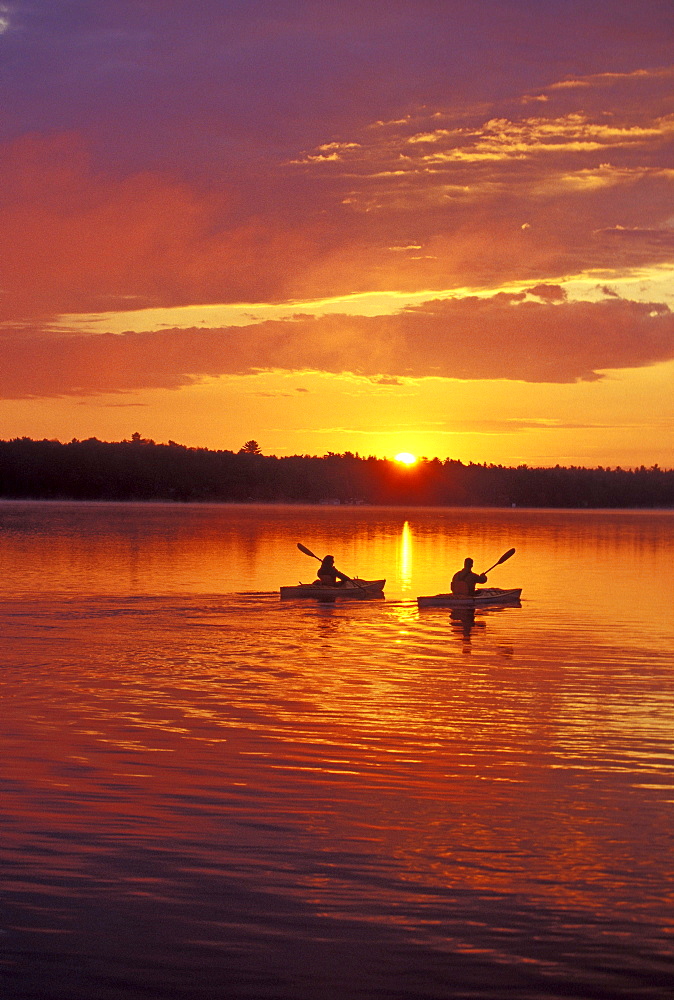 Young couple sea-kayak in early morning on Gull Lake near Bracebridge, Muskoka, Ontario, Canada.