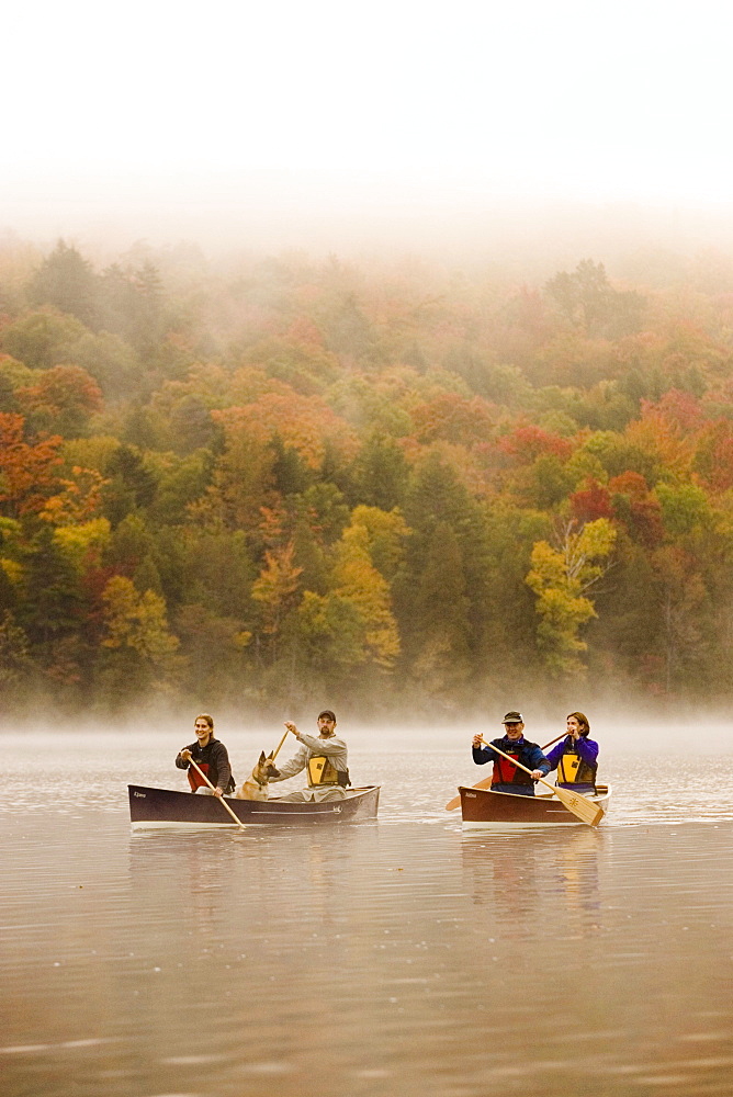 Two young couples canoe on Lake Placid on early autumn morning, Lake Placid, New York, USA.