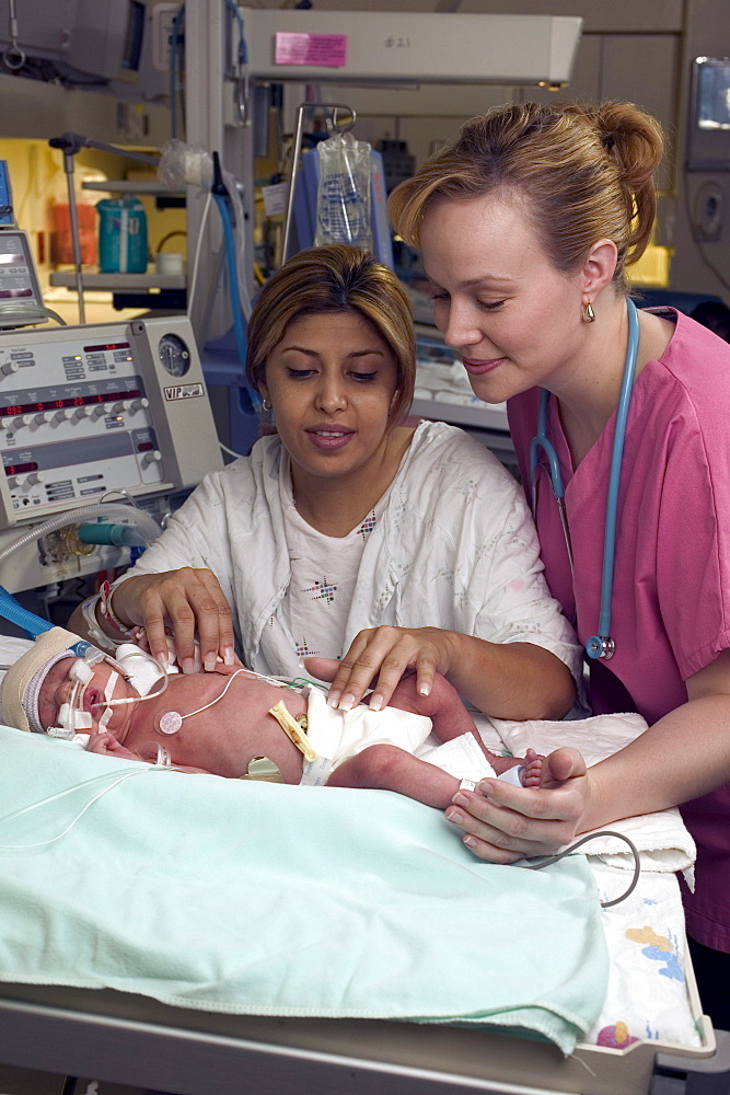 A nurse checks vital signs on a  premature child as it rests.