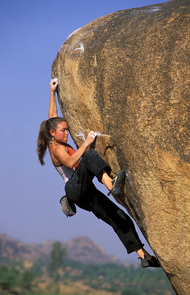 Katie Brown sucks it up as she nears the top of an overhanging bouldering route. Katie Brown, one of the world's leading sport climbers and the first  woman to flash a 5.14a sport route, is bouldering near the Hampi, ruins outside of Hampi, India.