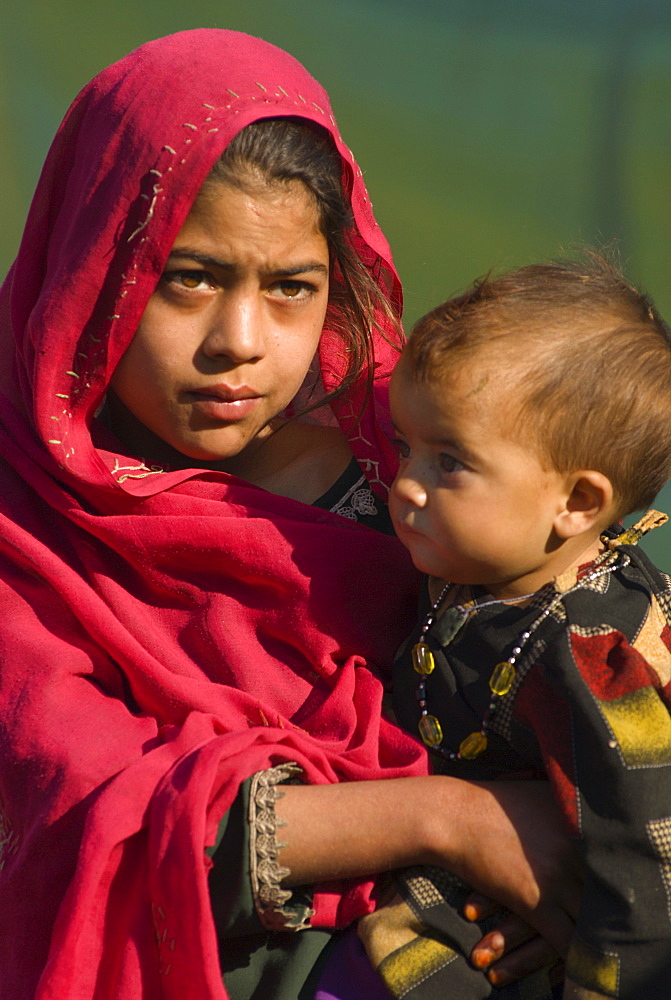 A Pashtun girl holds her younger brother, in the Meira camp for earthquake survivors in the Northwest Frontier Province, Pakistan.  The Meira Tent camp (also called Mera, or Maria camp), is located on the Indus River in the Battagram district.  The camp, the largest for displaced people in Pakistan, hosts over 21,000 earthquake survivors, primarily from the Allai valley in Pakistan's NWFP, one of the areas worst-hit by the October 8, 2005 earthquake.