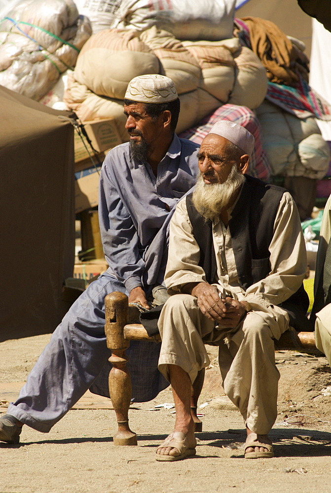 In the Meira camp for earthquake survivors, two Pashtun men sit by piles of family possesions, waiting for the truck which will take them from the camp, where they have spent the winter, back to their devastated mountain village, in the Northwest Frontier Province, Pakistan. The Pakistani army, which runs the camp, has mandated that the camps be cleared by early April, despite the fact that many families are afraid or unprepared to return to their devastated homes. The Meira Tent camp (also called Mera, or Maria camp), is located on the Indus River in the Battagram district.  The camp, the largest for displaced people in Pakistan, hosts over 21,000 earthquake survivors, primarily from the Allai valley in Pakistan's NWFP, one of the areas worst-hit by the October 8, 2005 earthquake.