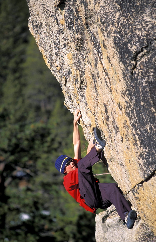 Young male rock climber Scott Corey bouldering at Echo Estates in the Sierra Nevada mountains, Lake Tahoe, California.