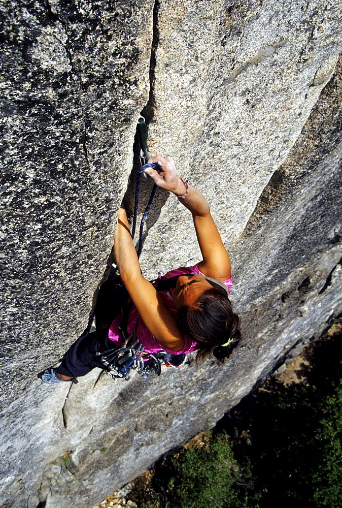 Dana Ikeda leading a steep crack climb struggles trying to clip protection in Yosemtie national Park Califorinia.