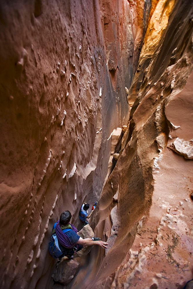 Three people descending a slot canyon, Utah.