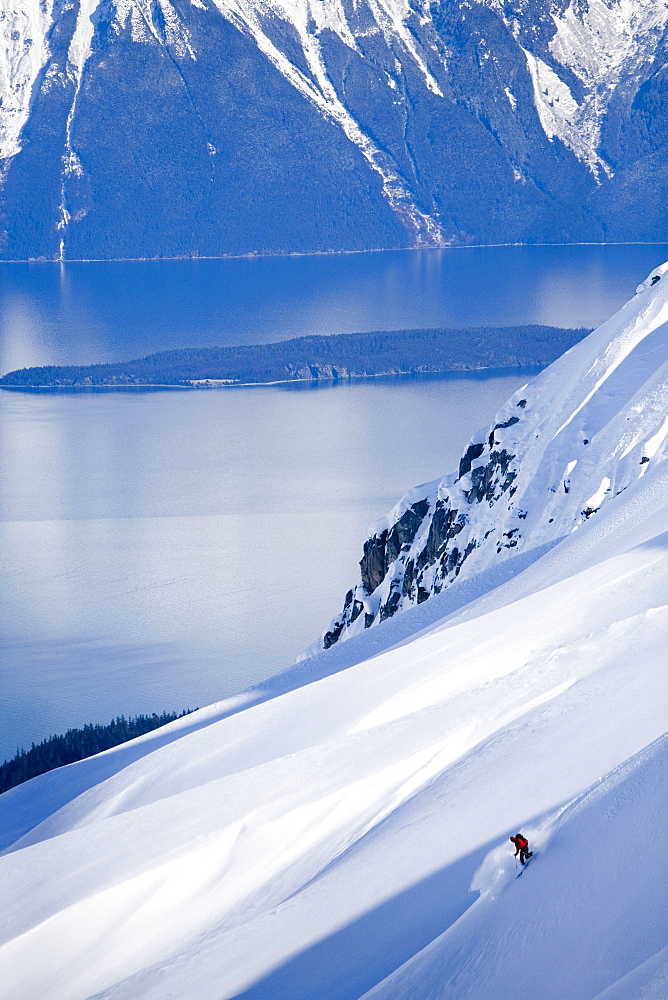 Telemark skier descends steep mountain in backcountry of southeast Alaska.