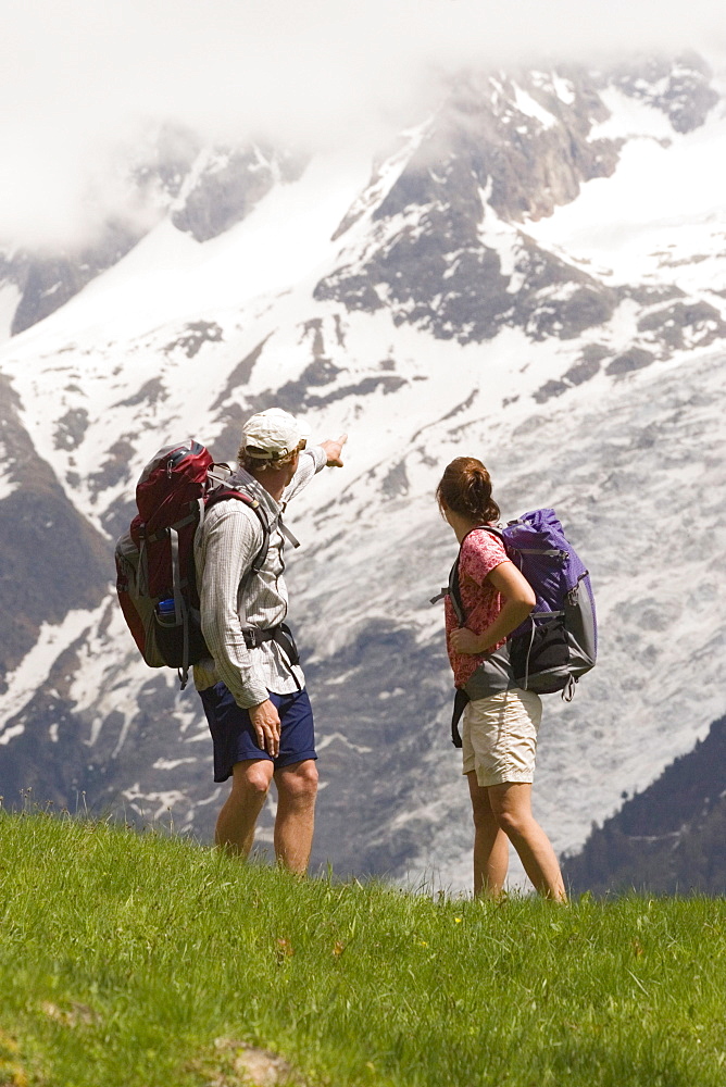 Two people hike by Mont Blanc near Les Houches, France.