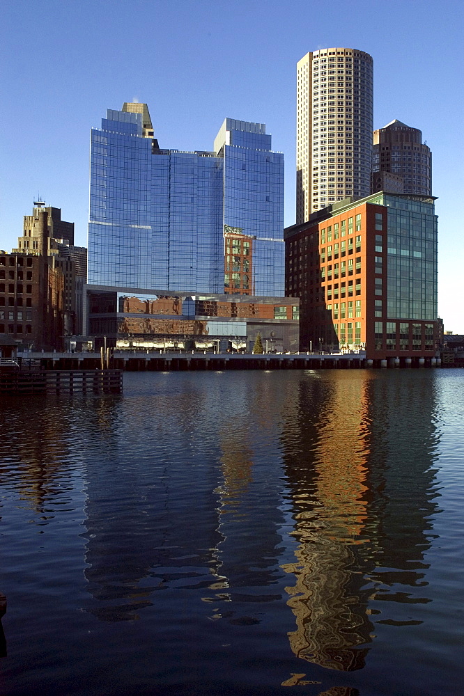 Cityscape. Boston's skyscrapers, illuminated by a late afternoon sun, are reflected in the water.