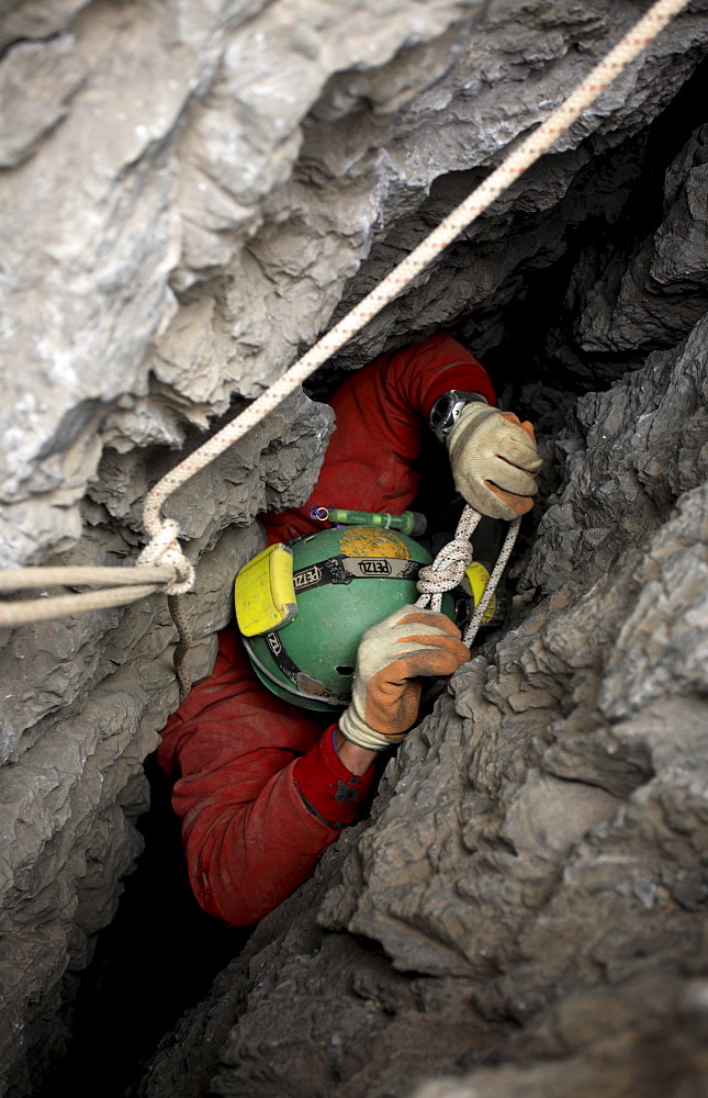 Cave explorer struggles to negotiate a tight squeeze in the entrance of a cave in the White Mountains on the island of Crete.