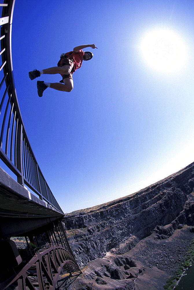 A BASE jumper jumps off of a bridge in Twin Falls, Idaho (Wide Angle Lens, Low Angle Perspective).