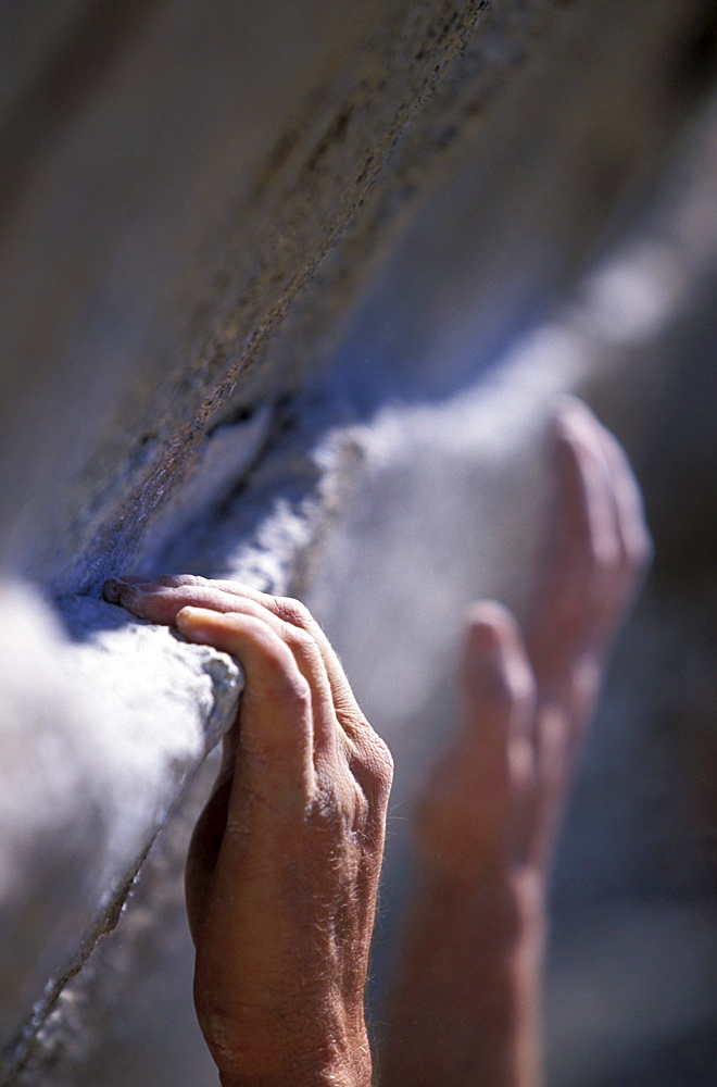 Close up of a climber's hands holding onto and reaching for a small ledge in Cordillera Blanca, Peru (Selective Focus).