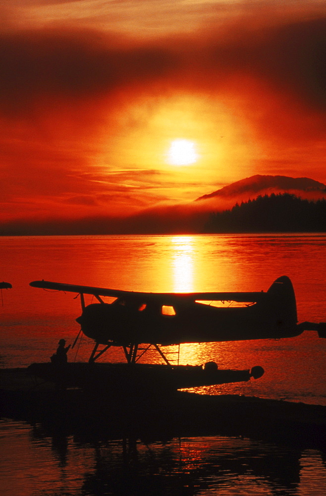 A pilot prepares his float plane (amphibious) for take-off at sunrise in Ketchikan, Alaska.