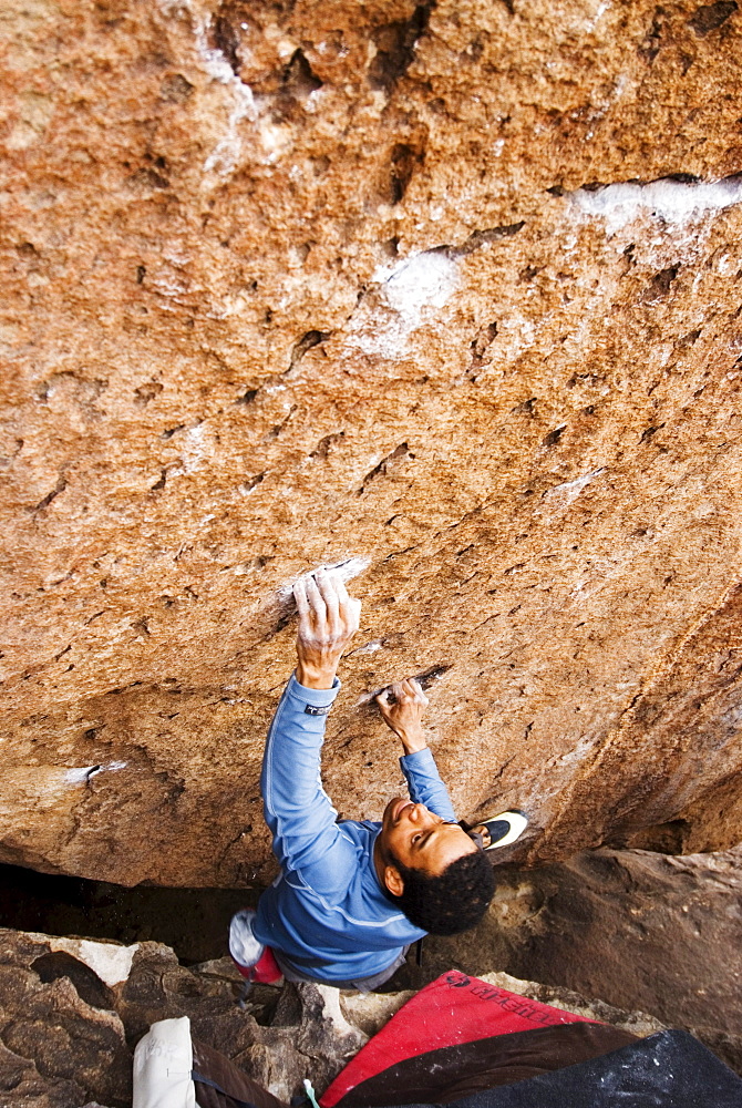 A Young African American man boulders in Hueco Tanks State Park near El Paso, Texas.