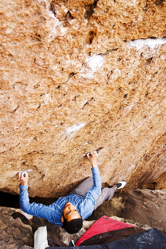 A Young African American man boulders in Hueco Tanks State Park near El Paso, Texas.