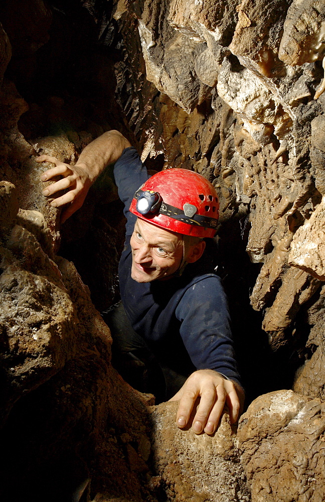 A cave explorer pushes his way through a tight section of cave