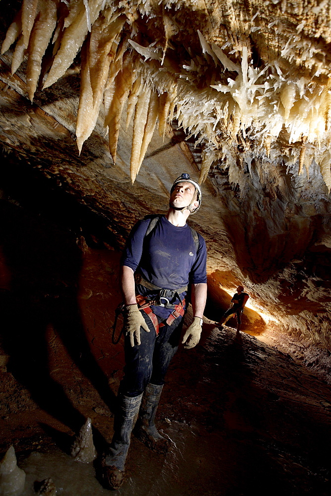 Fascinated by the pretty formations, this cave explorer poses for scale next to a cluster of Stalactites deep in Moon Cave.