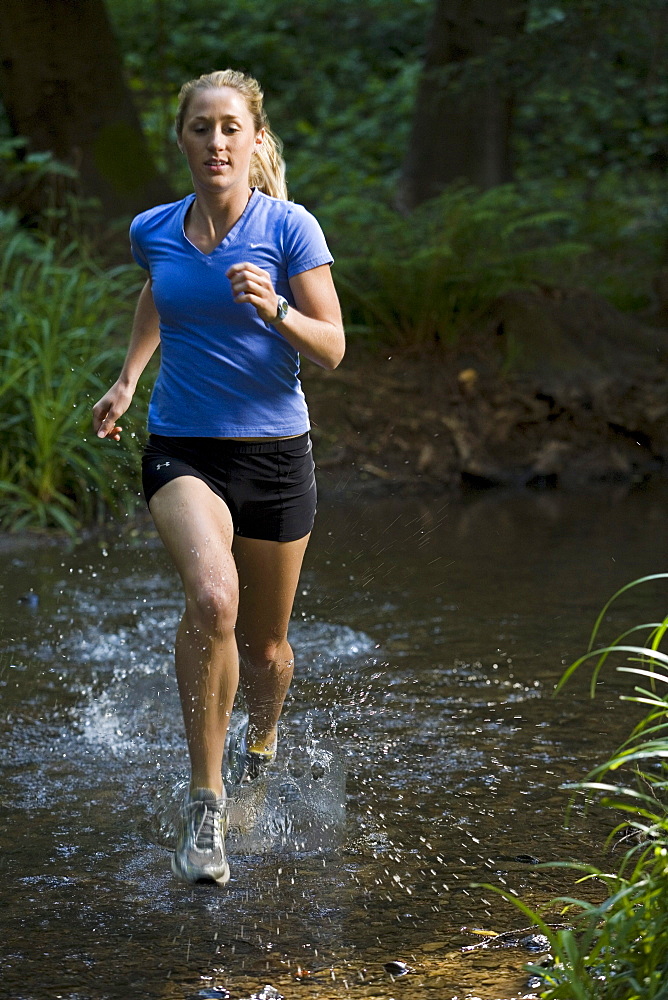 In the darkness of a redwood forest, a runner crosses a stream.