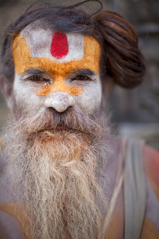 A Hindu priest, a sadhu and esthetic, with body paint poses in a Kathmandu, Nepal temple.