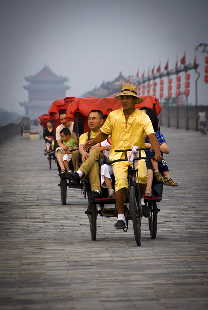 Rickshaw drivers carrying tourists on top of the Xian City Wall. Xian, Shaanxi Province. China