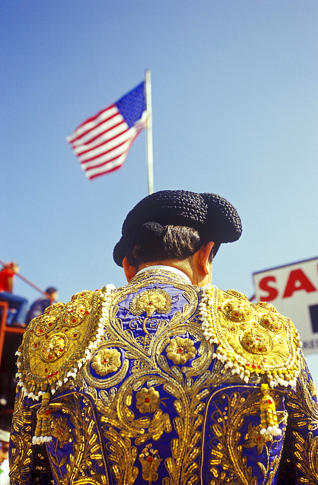 Matador stands underneath the American flag before the start of a bullfight.