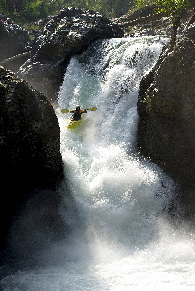 Young kayaker dropping into a large rapid / waterfall in the jungle in Mexico.