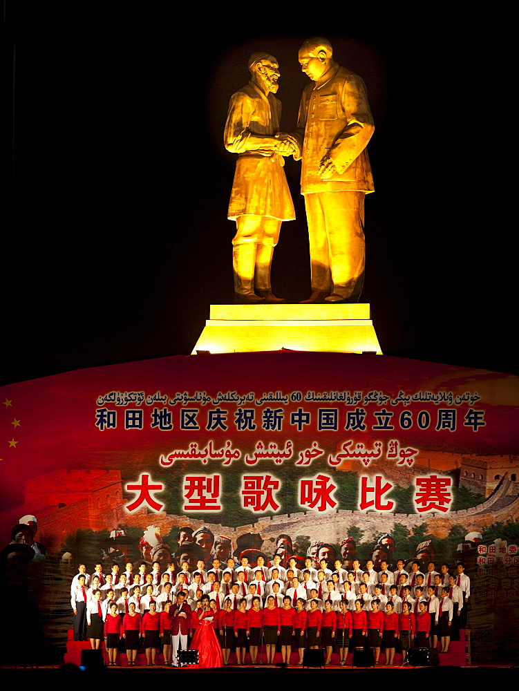 Culture performance under a statue of Mao and a senior Uyghur man in Hotan, Xinjiang, China.