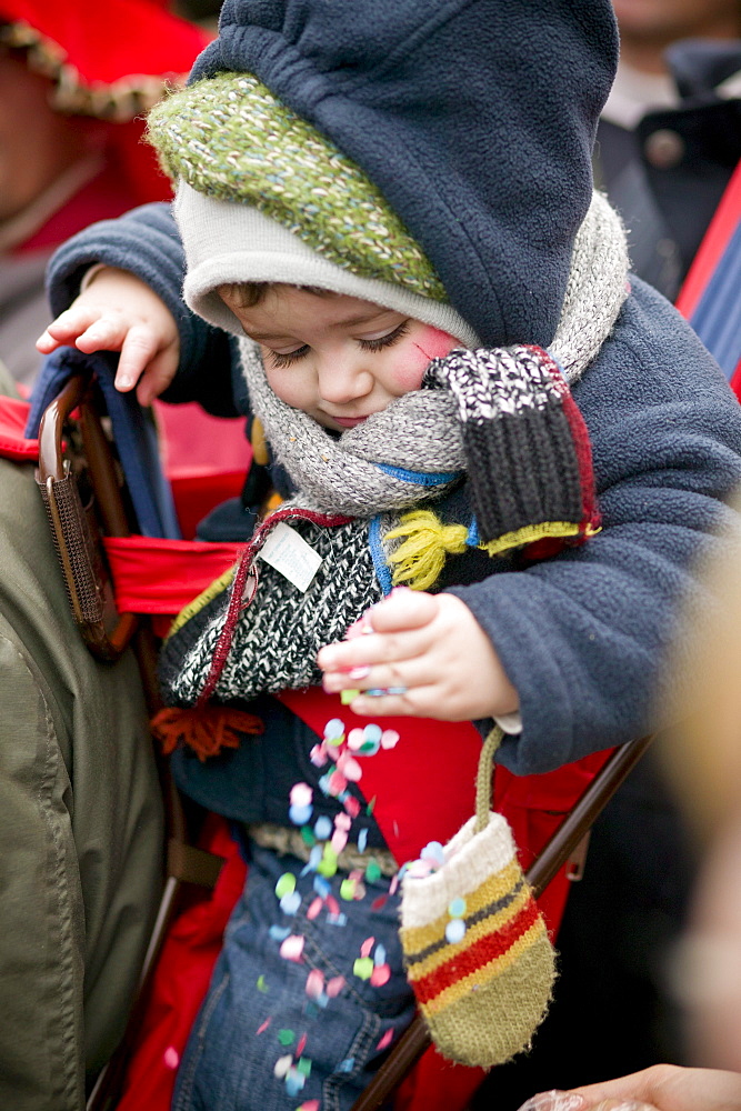 A young carnival viewer enjoys the colorful confetti that is thrown during the Carnival of Binche in Belgium.