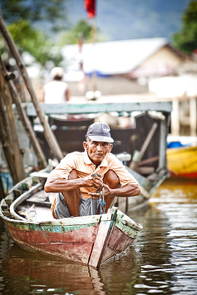 A man peers out from his small fishing boat near the dock in Sukadana, Indonesian Borneo.