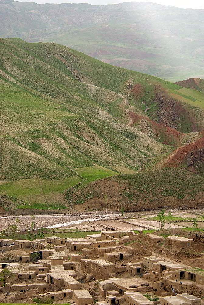 Mud houses cluster below  steep hills and along a seasonal river, in the village of Dera Jawal, at the base of the Band-e Baba range,  Herat Province, Afghanistan