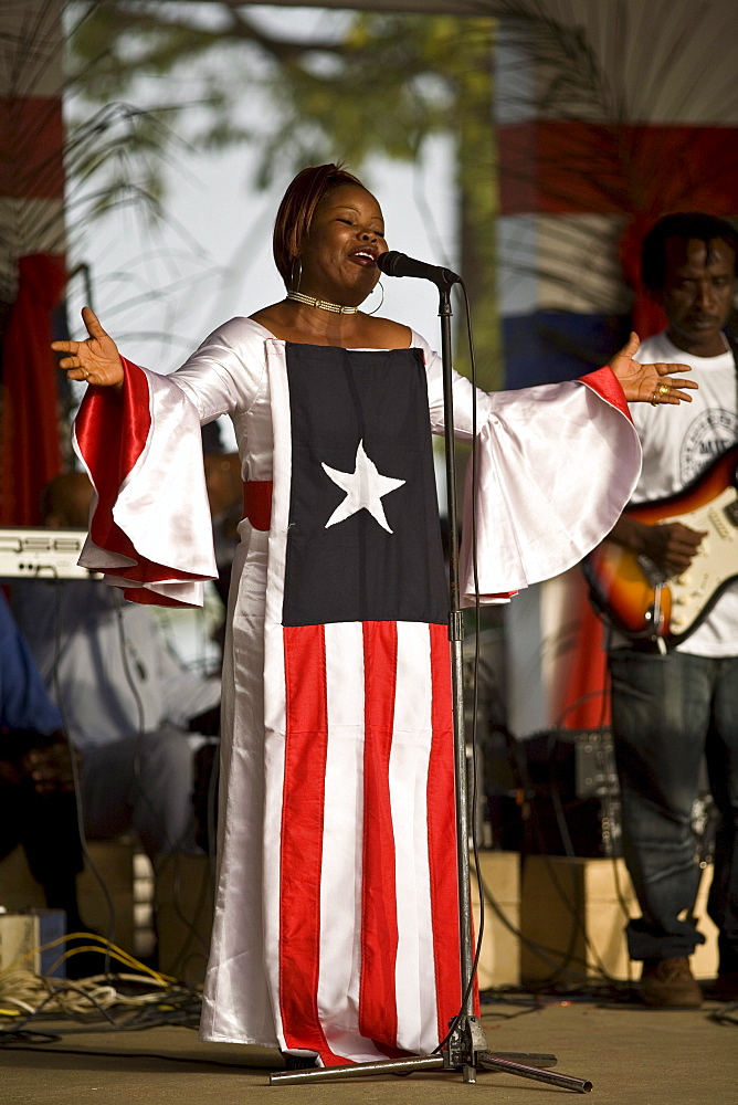 Young Liberian woman wearing a dress with the Liberian flag on it, singing the national anthem during a celebrations in Monrovia, Liberia on January 17th, 2007 marking one year anniversary of President Ellen Johnson Sirleaf coming to power.