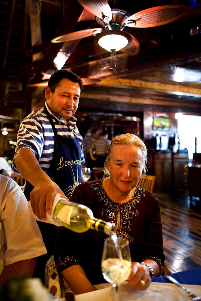 A waiter pours white wine for a guest at a restaurant in Cancun, Mexico.