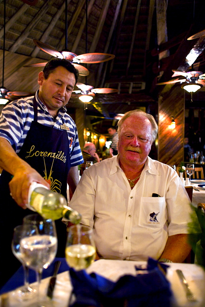 A waiter pours white wine for a guest at a restaurant in Cancun, Mexico.