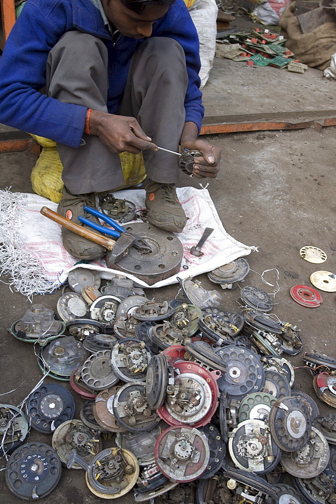 At a scrap metal market in New Delhi, India old rotary phone are disassembled for the metals.